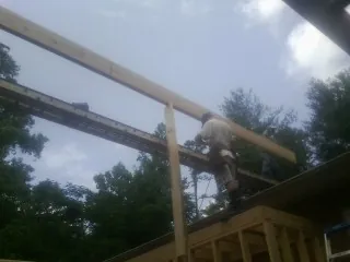 Carpenter setting a ridge beam over a new addition frame — Ice Dam Removal by Roofing Brothers in Arrington