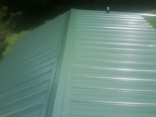 New green metal panels meeting at the ridge of a roof — Flat Roof Repair work by our crew in Arrington