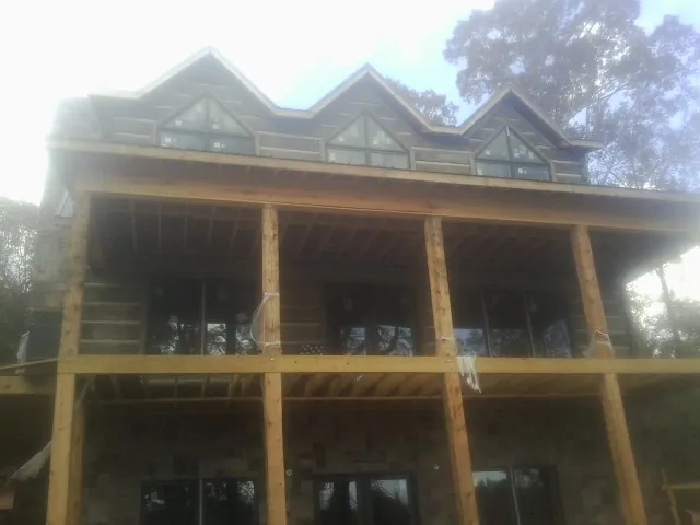 Dormers and porch framing on a large log home under construction — Roof Coating work by our crew in Arrington