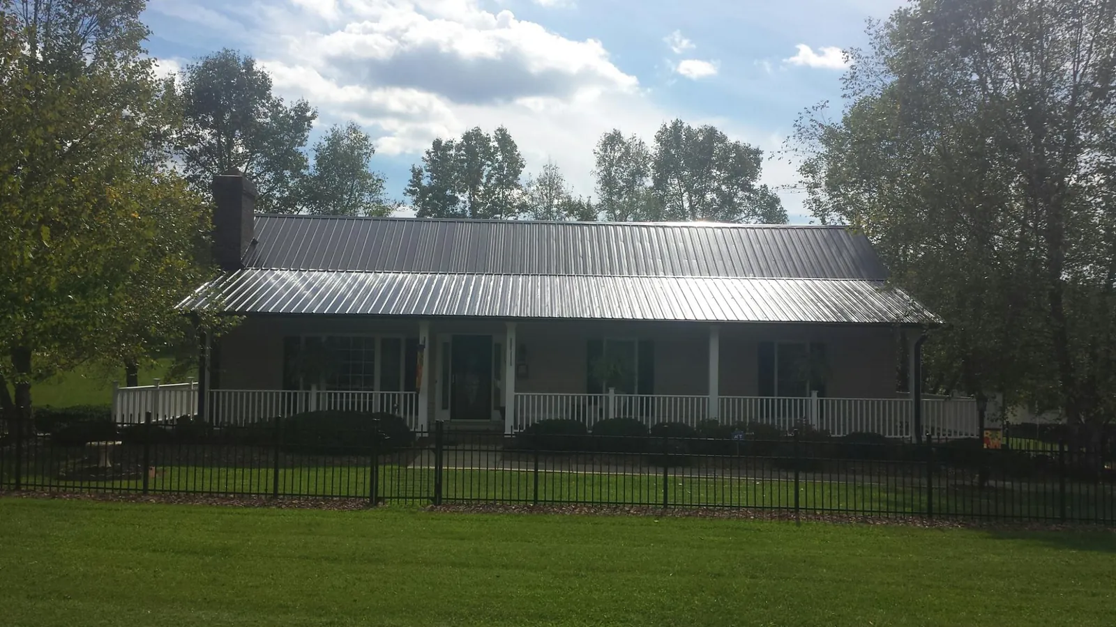 Gray metal roof on a brick ranch with a full width front porch — Gutter Guard Installation work by our crew in Arrington