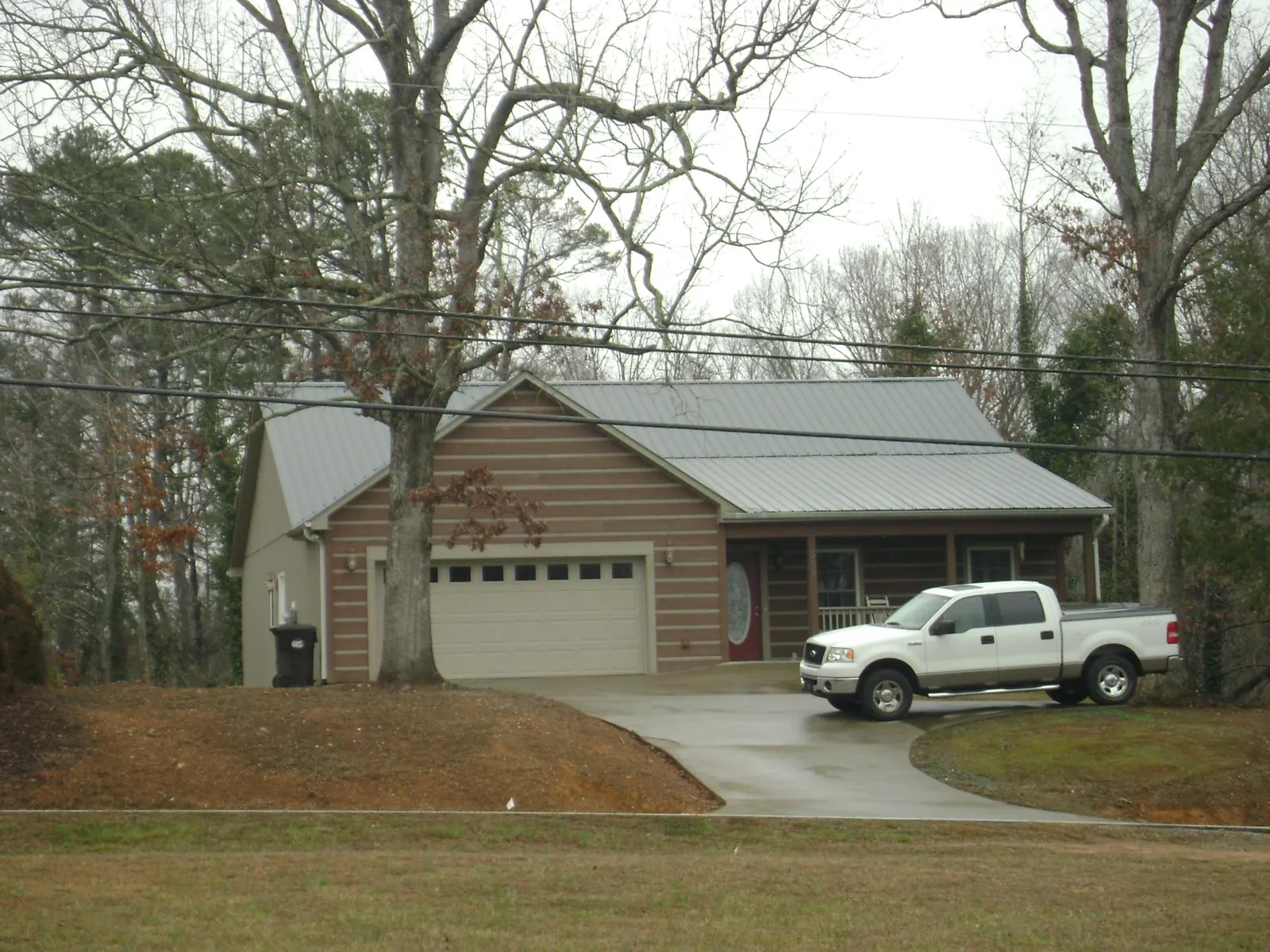Gray metal roof on a log sided house with an attached two car garage in Arrington