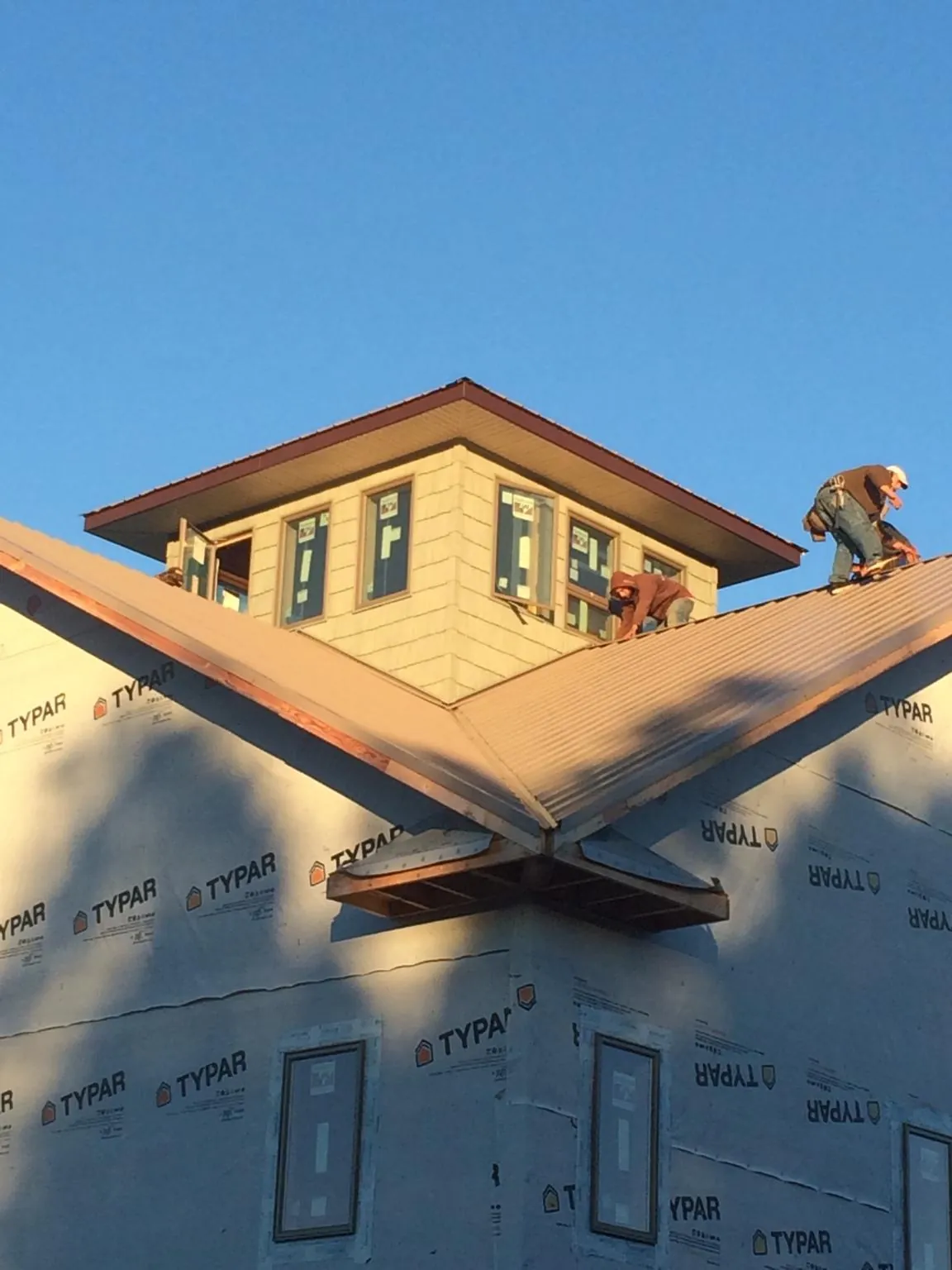 Roofers working around a rooftop cupola on a new metal roof at sunset — Roof Waterproofing in Arrington by Roofing Brothers